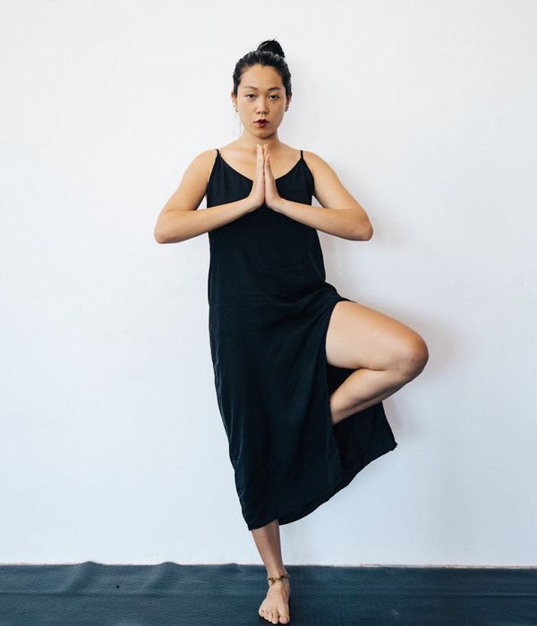 Woman practicing yoga balance pose in a dark minimalist studio